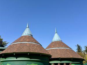 Two round green buildings with pointed cone-shaped roofs under a clear blue sky. Photographed at the Oregon Zoo in Portland, Oregon. 