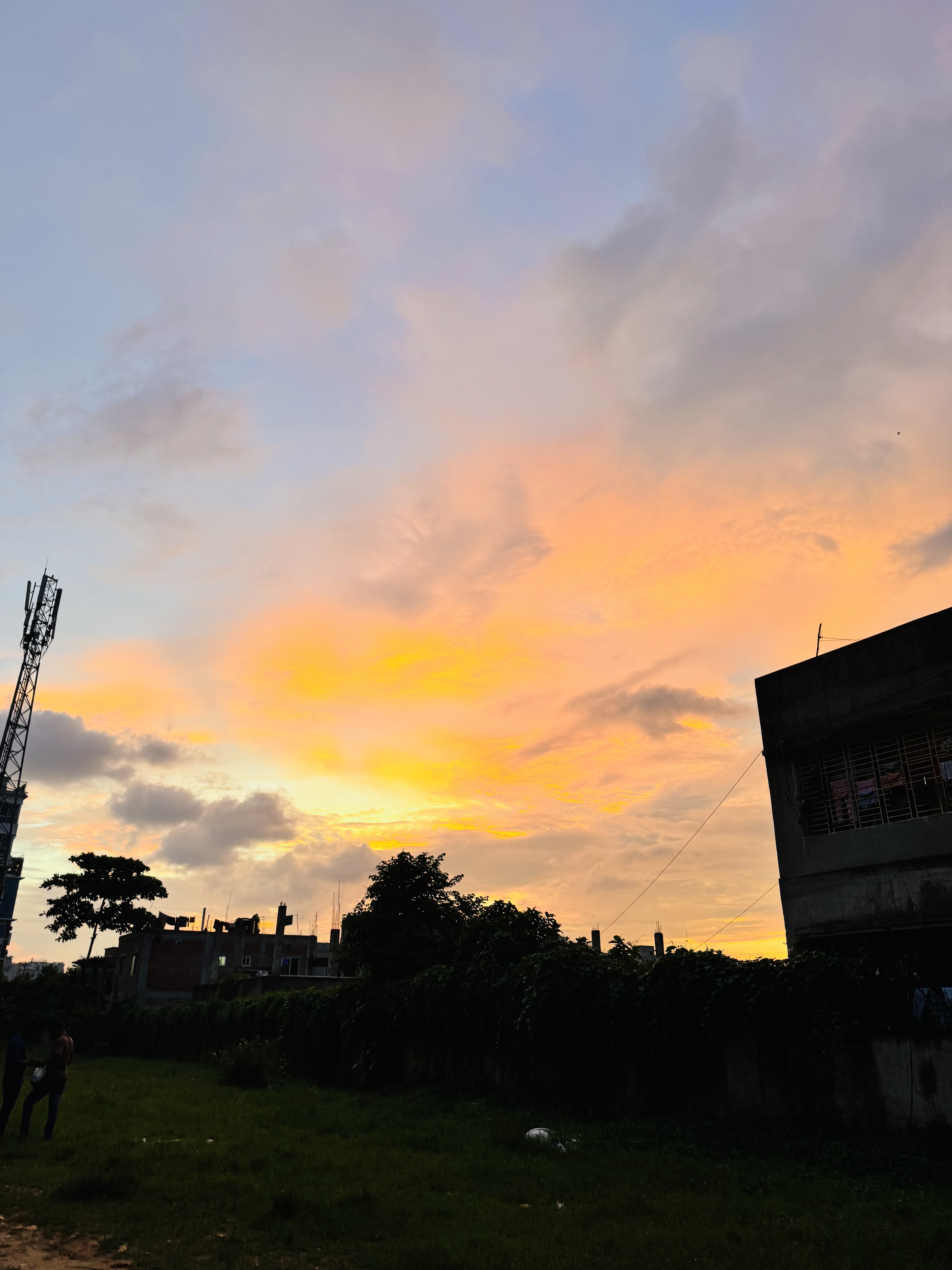 A vibrant sunset fills the sky with hues of orange and yellow, contrasted against the soft blue of the twilight.