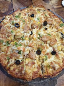 A close-up view of a baked pizza on a wooden serving board. 