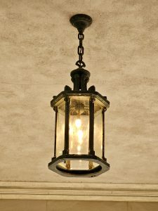 Close-up of an antique hanging lantern under a ceiling at Pittock Mansion, Portland. The warm evening glow makes the details of the glass and metal pop.