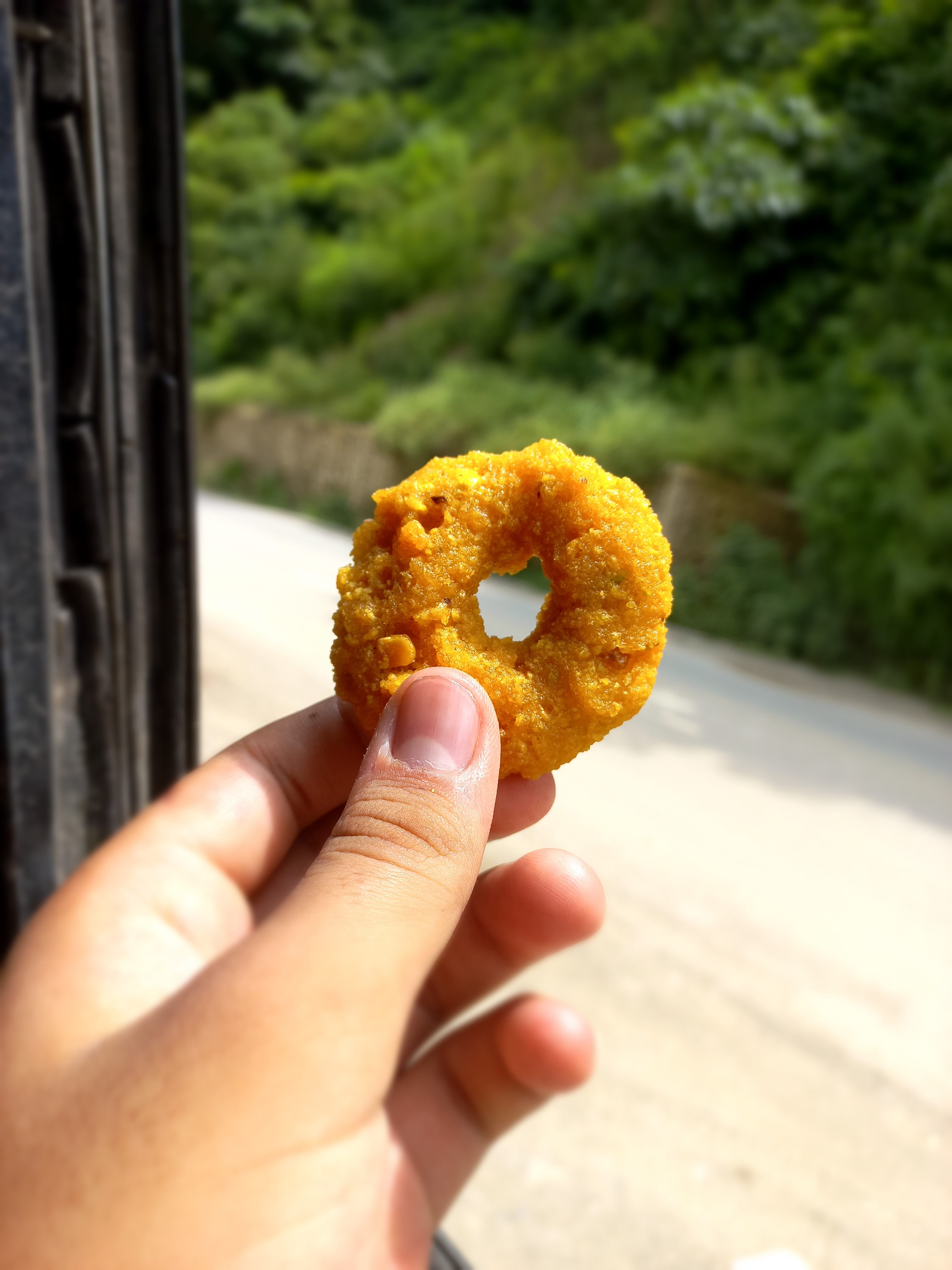 A person holding a glazed donut in their hand, showcasing its round shape and sprinkles on top.