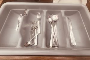 A cutlery tray filled with clean forks, spoons, and knives.