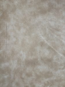 A soft beige textured surface with subtle shading, complemented by a cozy sofa seat.