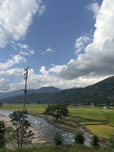 A picturesque landscape featuring a flowing river bordered by lush green fields.