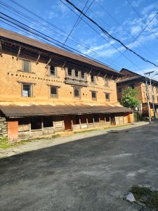 A street scene featuring a large, traditional brick building with wooden window frames and decorative elements.