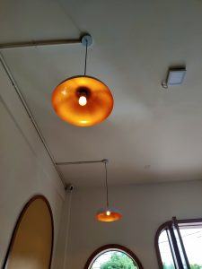 Two pendant lights hang from the ceiling, one with a wide, orange shade and a visible bulb, and another with a blue-gray shade that also emits light