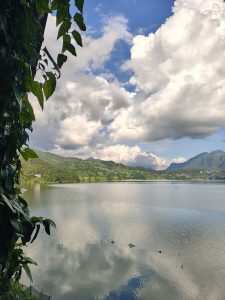 A serene landscape featuring a calm lake reflecting the sky and surrounding hills