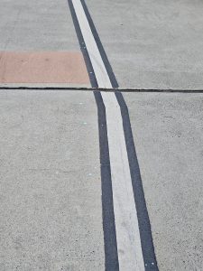 A minimalistic close-up of a white line with a curve on the sidewalk pavement near Tilikum Crossing Bridge, Portland. 