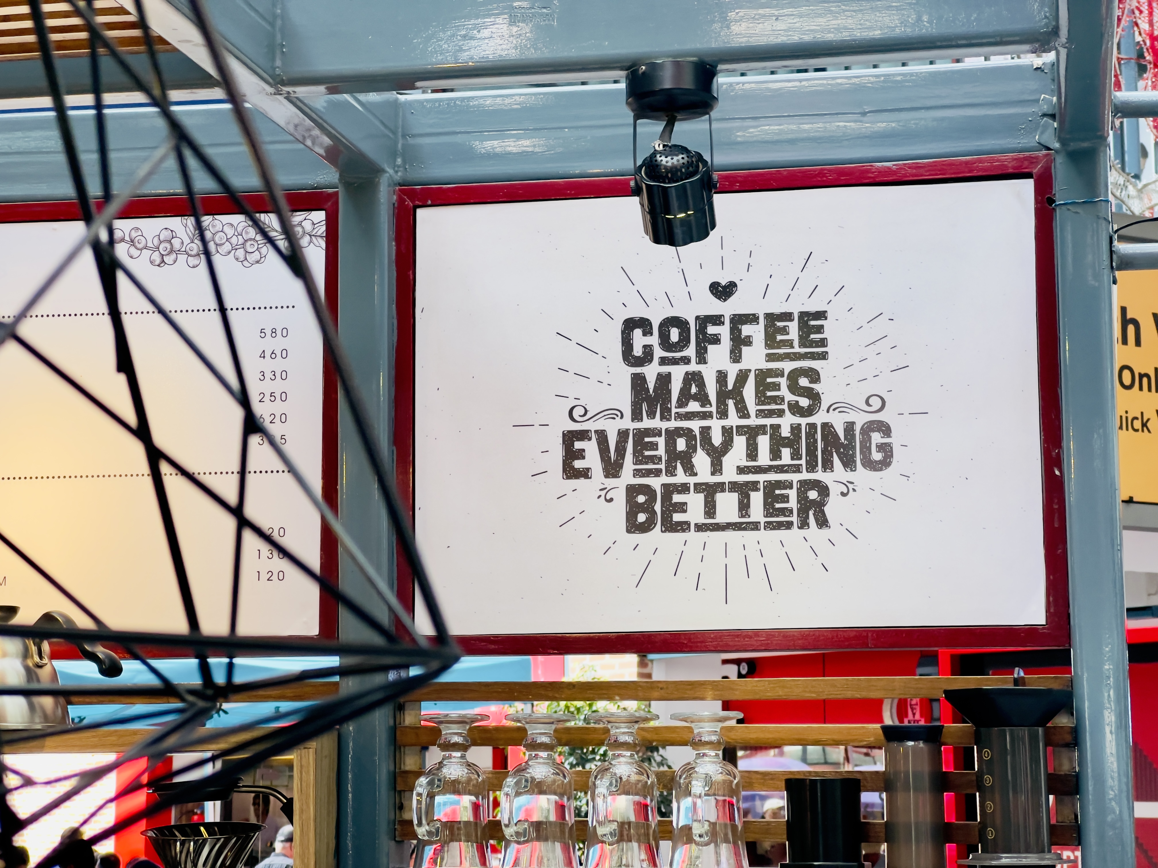 A sign that says "COFFEE MAKES EVERYTHING BETTER" is pictured on the front of a cafe counter.