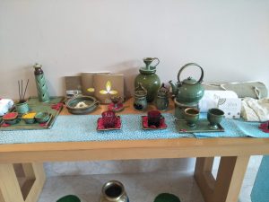 A beautifully arranged table featuring a variety of green ceramic tea sets, including a kettle, cups, and small dishes.