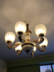 A decorative ceiling chandelier with a central white fixture surrounded by six spherical glass shades, each emitting warm light