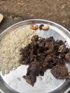 A silver plate holds spiced dark meat with onions and a serving of flattened rice.