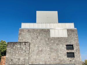 Modern stone building under a deep blue sky in Washington Park, Portland, Oregon. The sunlight reflects on the top panels, giving a clean and geometric look. 