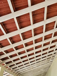 An angled view of a tiled roof with red clay tiles and a white wooden frame, seen from below in Kozhikode, Kerala.