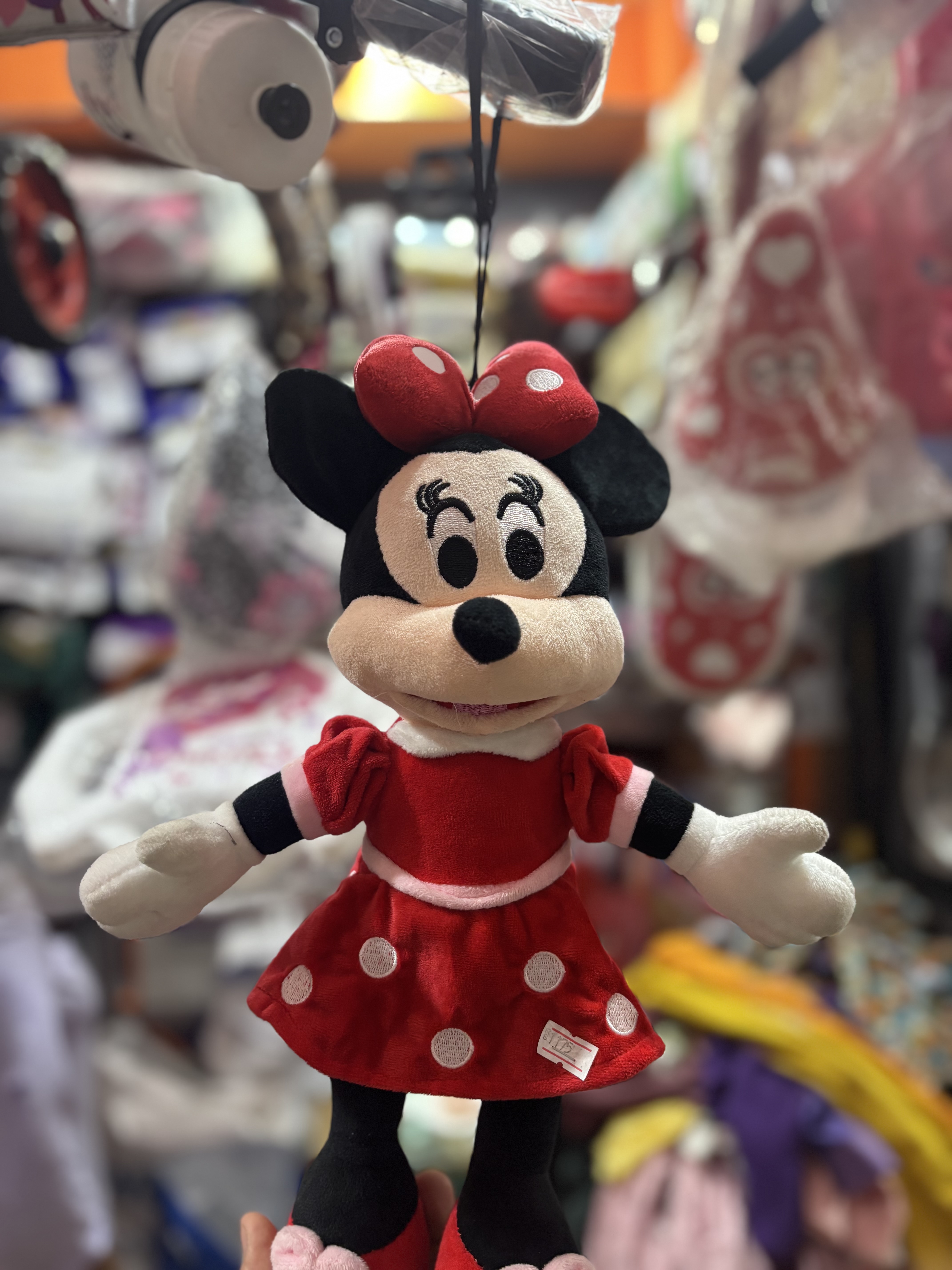 A plush toy of a female cartoon character, dressed in a red dress with white polka dots and a matching bow on her head.