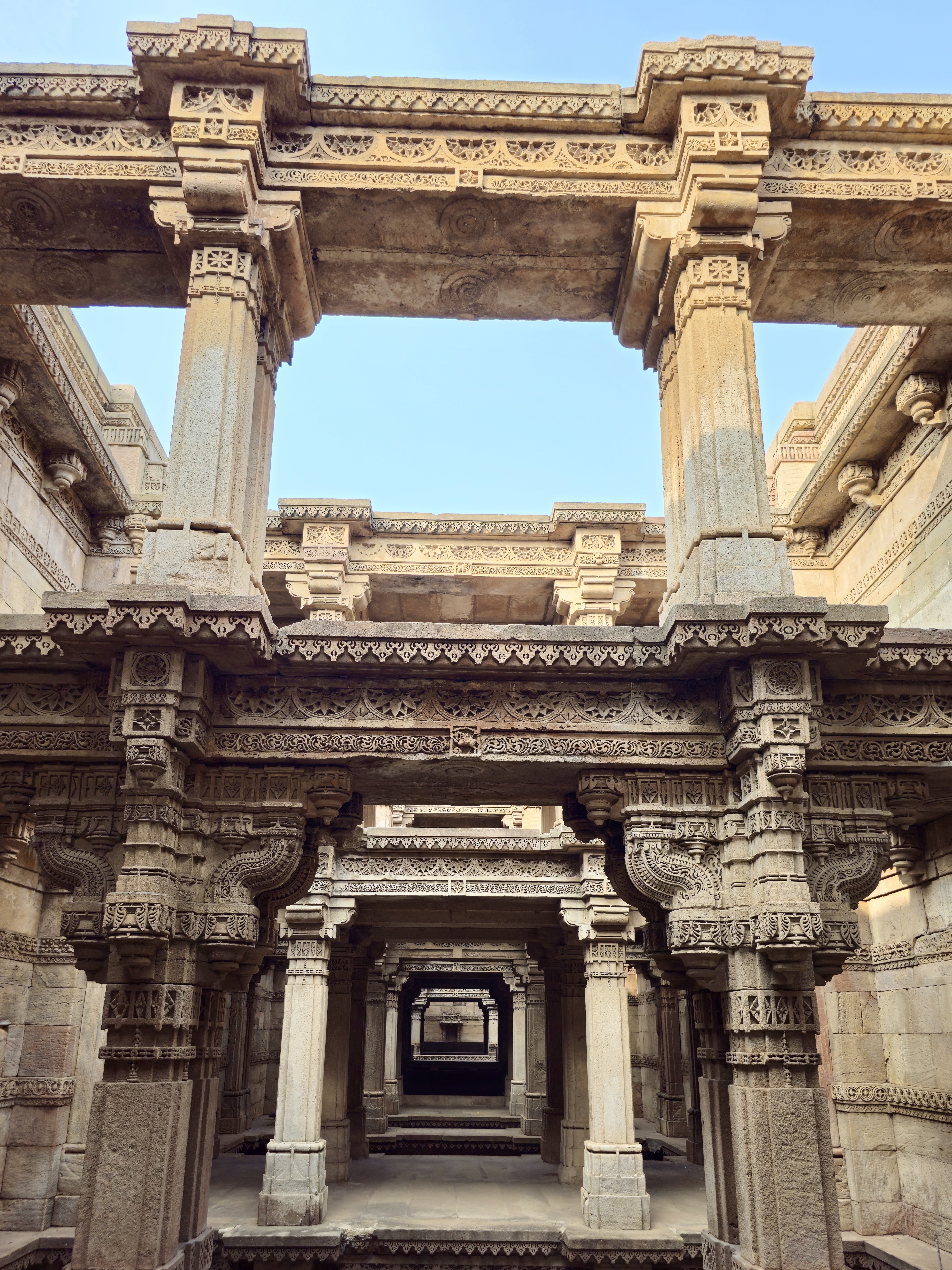 Rows of stone columns with floral patterns and detailed brackets support the stepped levels of Adalaj Stepwell (Gandhinagar, Gujarat).