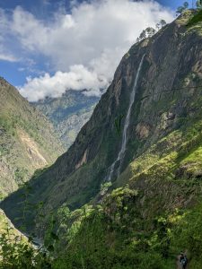 A breathtaking mountainous landscape featuring steep green hills and a cascading waterfall