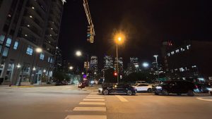 Traffic on a night time city street, at an intersection. A bright street light is in the center of the image.  Chicago.
