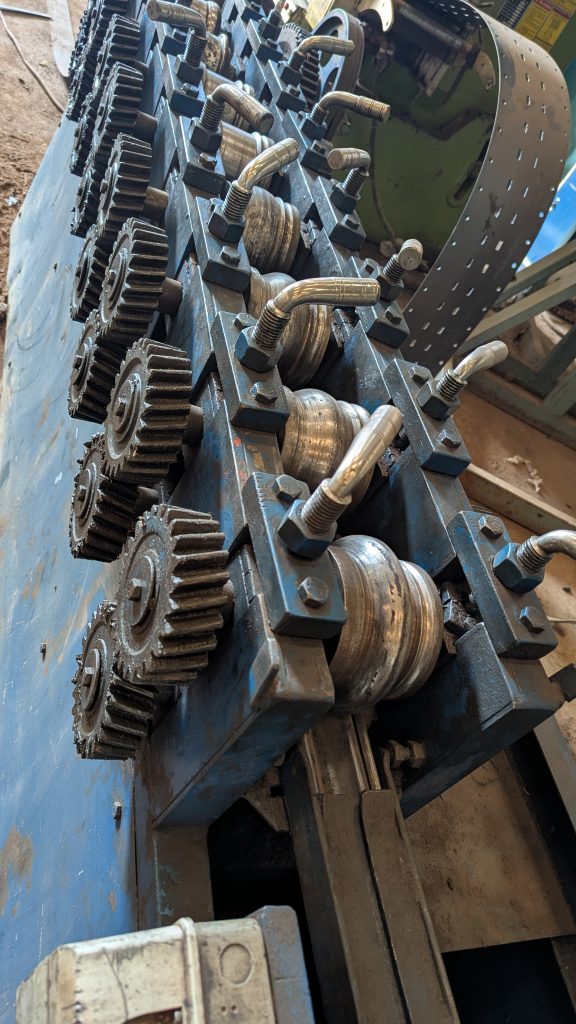 Metal cutting and rolling machine showing several mounted cogs