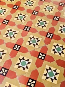 Old-fashioned geometric tiles with red, yellow, black, and green star motifs on the floor of Hill Palace, Thrippunithura, Kerala. 
