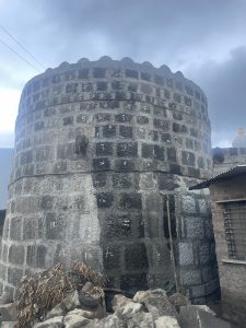 A cylindrical stone structure with a textured surface, featuring white numbers painted on its side.