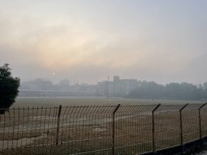 A winter morning at Brahmanbaria’s Niaz Mohammad Stadium is calm and misty. The soft fog gently covers the field, while players warm up in the chilly breeze. The sun rises slowly, casting a golden glow over the dew-kissed grass- creating a peaceful and refreshing start to the day.