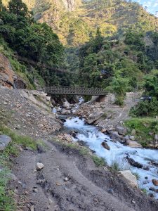 A serene mountain landscape featuring a clear, flowing river surrounded by lush greenery.