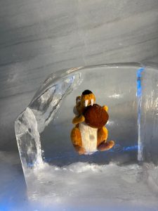A plush toy of a cartoon character, positioned inside a transparent ice block.
