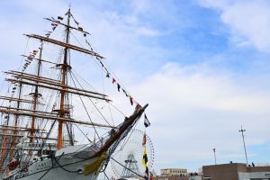 

A majestic tall ship with colorful flags docked at a waterfront in Yokohama, Japan.
