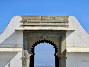 A front view of an arched stone doorway at Monsoon Palace, Sajjangarh, Udaipur. The sky and the city of Udaipur can be faintly seen through the arch. The frame's symmetry stands out clearly.