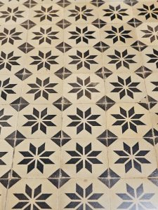 A patterned floor at Hill Palace, Thrippunithura, Kerala. The classic tile design features repeated black stars on beige tiles, preserving a vintage style. 