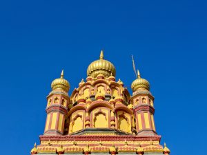 Bright red and yellow domes of the temple stand out against a clear blue sky. Shot at Parvati Hill, Pune.