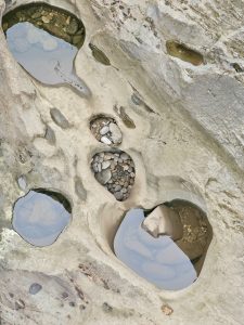 Multiple small pools of water formed in rock cavities, filled with pebbles and clear water after rainfall, and are a natural rock formation. Captured from the Chalipuzha River, near Thusharagiri Falls, Kozhikode. 