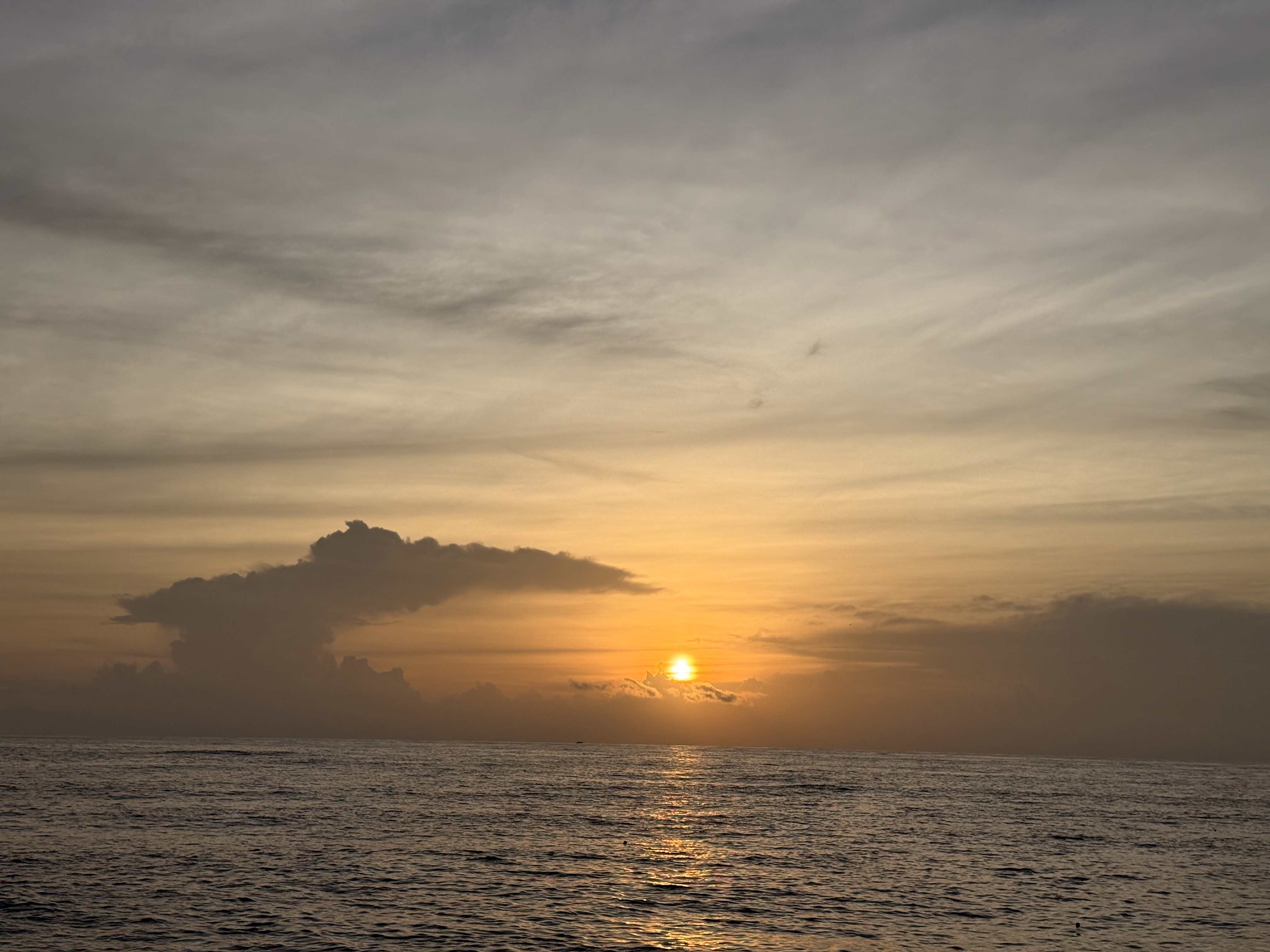 Sunset clouds with golden reflections on the water, casting soft light over Cherai Beach, Ernakulam.