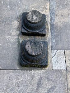 Two worn cylindrical stone pegs set in square bases, known as Balikallu, are used for making offerings to deities or spirits, photographed at Sree Shiva Vishnu Temple, Perumanna, Kozhikode.