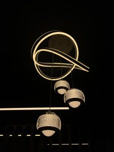 A modern ceiling light with interlocking white LED rings and three clear glass globe pendants.