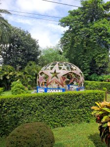 A vibrant outdoor scene featuring a decorative dome structure adorned with large stars, surrounded by lush greenery. 