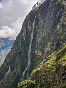 A majestic waterfall cascading down a steep rocky cliff surrounded by lush greenery