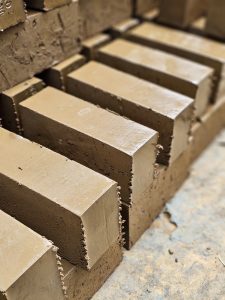 Freshly shaped wet clay bricks are arranged neatly after extrusion, taken in a brick factory in Perumanna, Kozhikode, Kerala. Still soft and awaiting drying. 