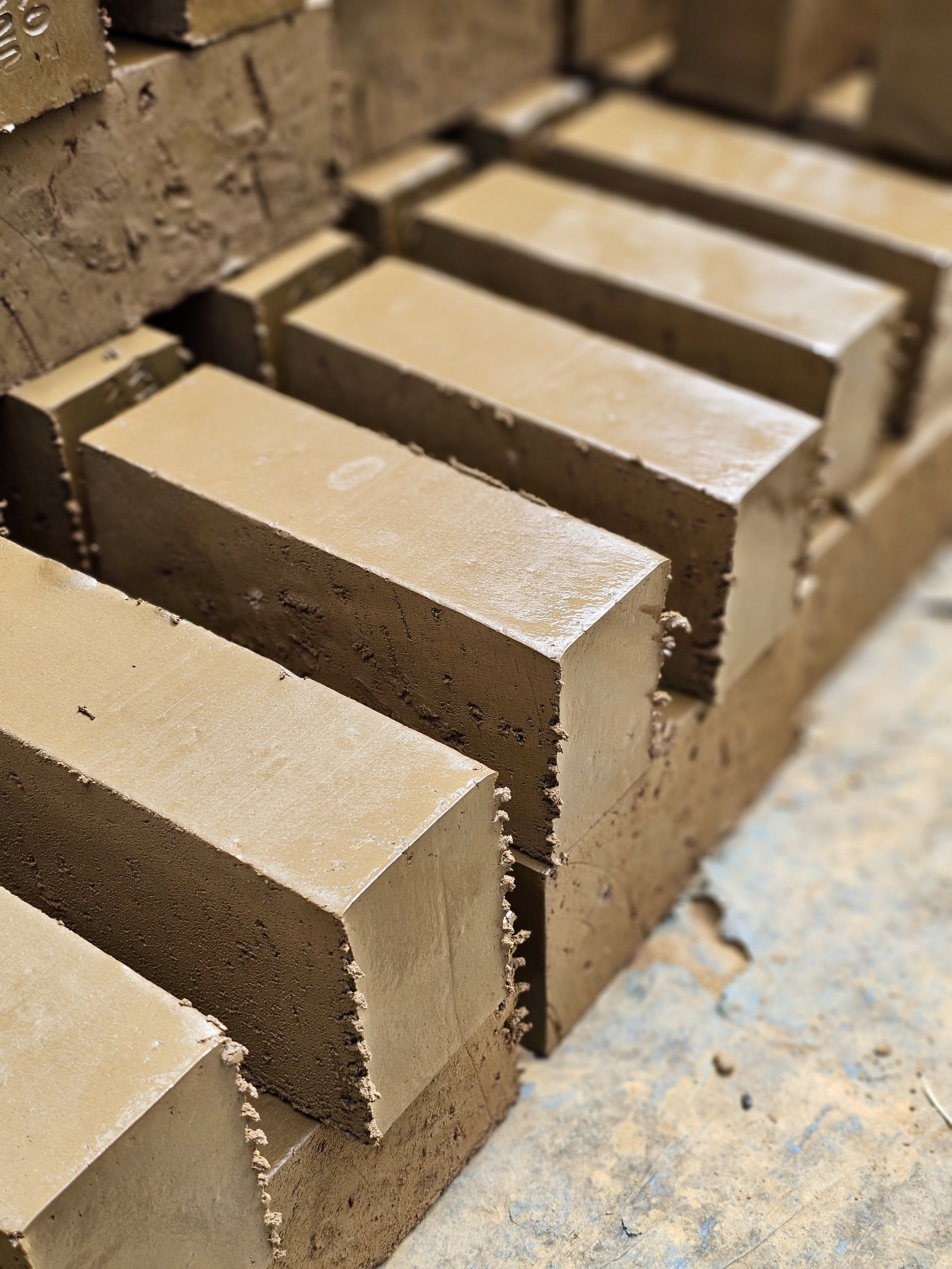 Freshly shaped wet clay bricks are arranged neatly after extrusion, taken in a brick factory in Perumanna, Kozhikode, Kerala. Still soft and awaiting drying. 