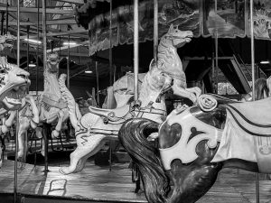 An antique carousel featuring a ride-on wooden cat with a fish in its mouth.