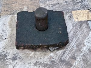An ancient-looking Shiva Linga made of dark stone, placed on a temple floor made of natural stone tiles, was captured from Sree Shiva Vishnu Temple, Perumanna. 