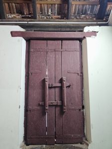 A sturdy wooden door with traditional crossbar locking is located inside Hill Palace, Thrippunithura, Kerala. 