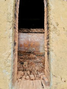 A framed view through the kiln entrance showing brick stacks ready for firing. Taken at a local brick kiln in Perumanna, Kozhikode, Kerala. 