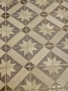 Textured tiles with embossed beige star shapes and brick-like patterns are seen at Hill Palace, Thrippunithura, Kerala. 