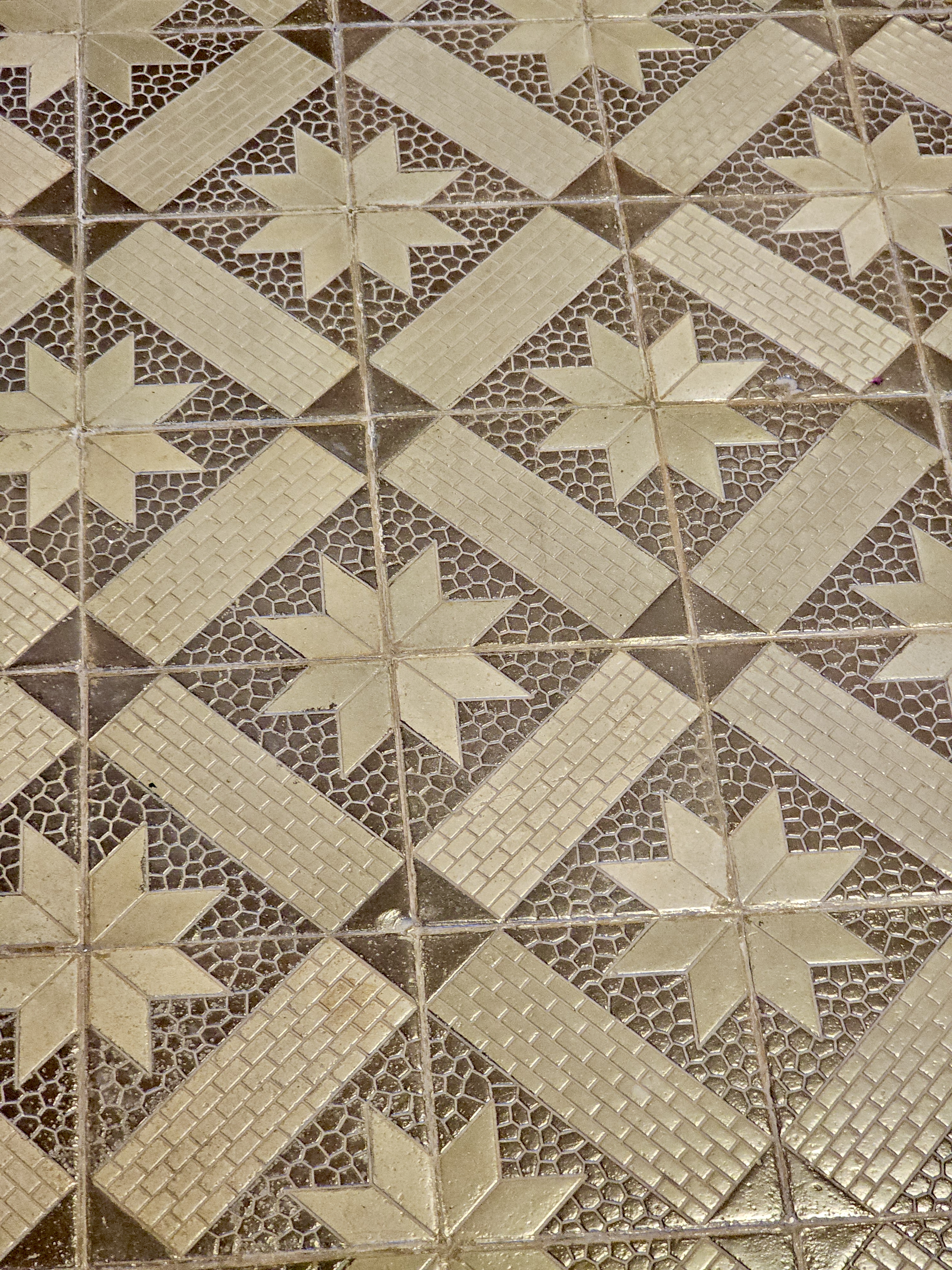 Textured tiles with embossed beige star shapes and brick-like patterns are seen at Hill Palace, Thrippunithura, Kerala. 