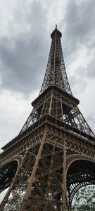 Looking up at Eiffel Tower against a grey, cloudy sky