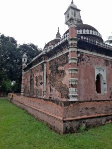 

Old brick building with domes and towers on a grassy lawn.
