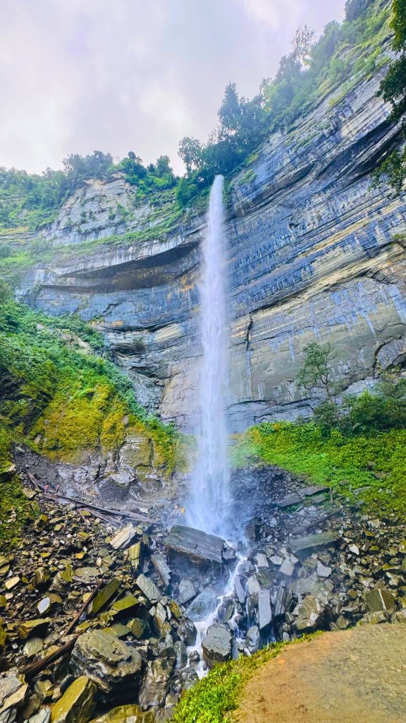 Langlok Waterfall in Bandarban, Bangladesh, cascades down a rocky cliff surrounded by lush greenery.