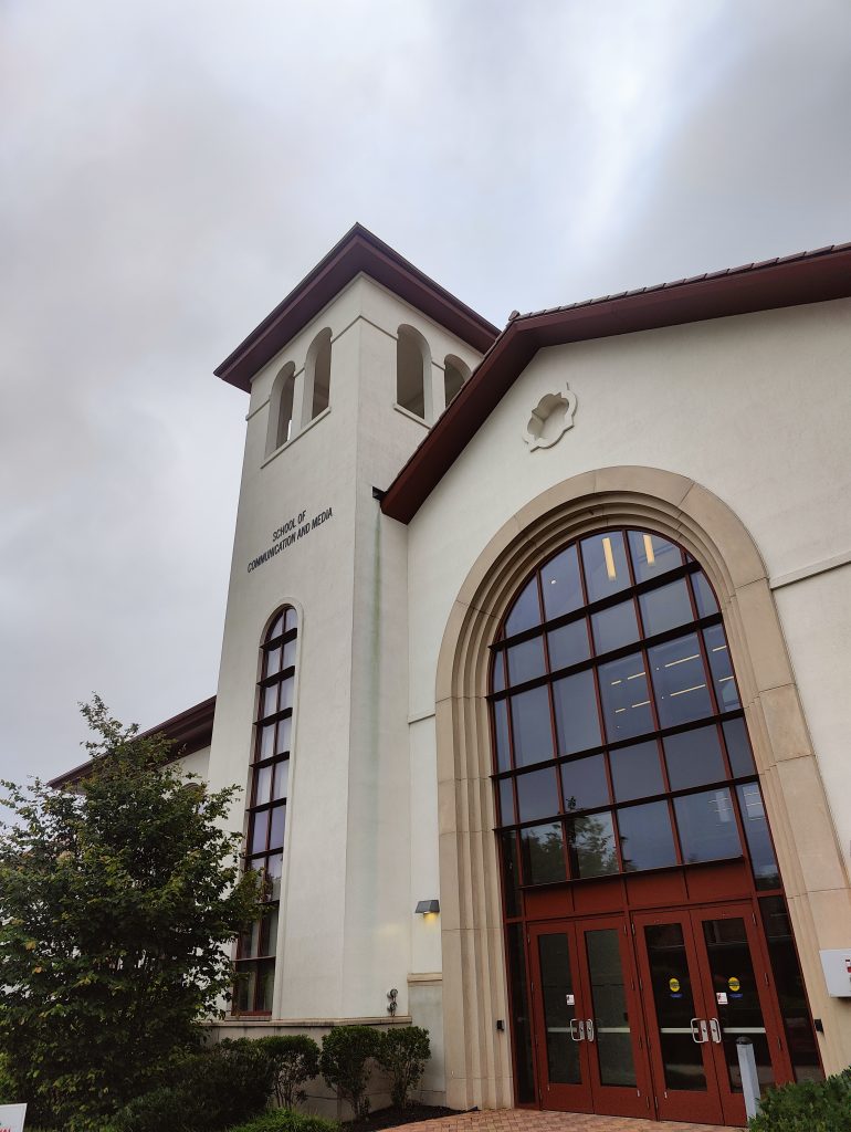 An image of a building of the School of Communication and Media at the University of Montclair with a cloudy sky in its background. Venue of WordCamp Montclair 2025